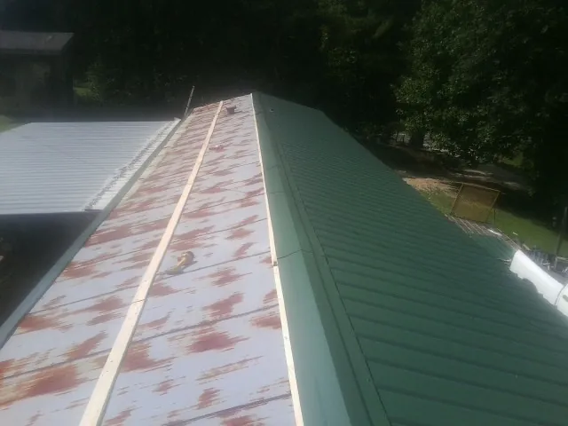 Old rusted panels beside newly installed green metal roofing — Wind Damage Roof Repair by Roofing Brothers in Hemlock