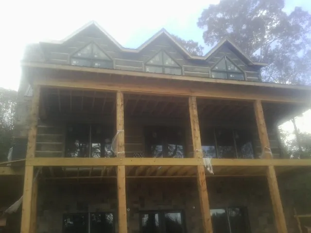 Dormers and porch framing on a large log home under construction — Roof Coating work by our crew in Hemlock