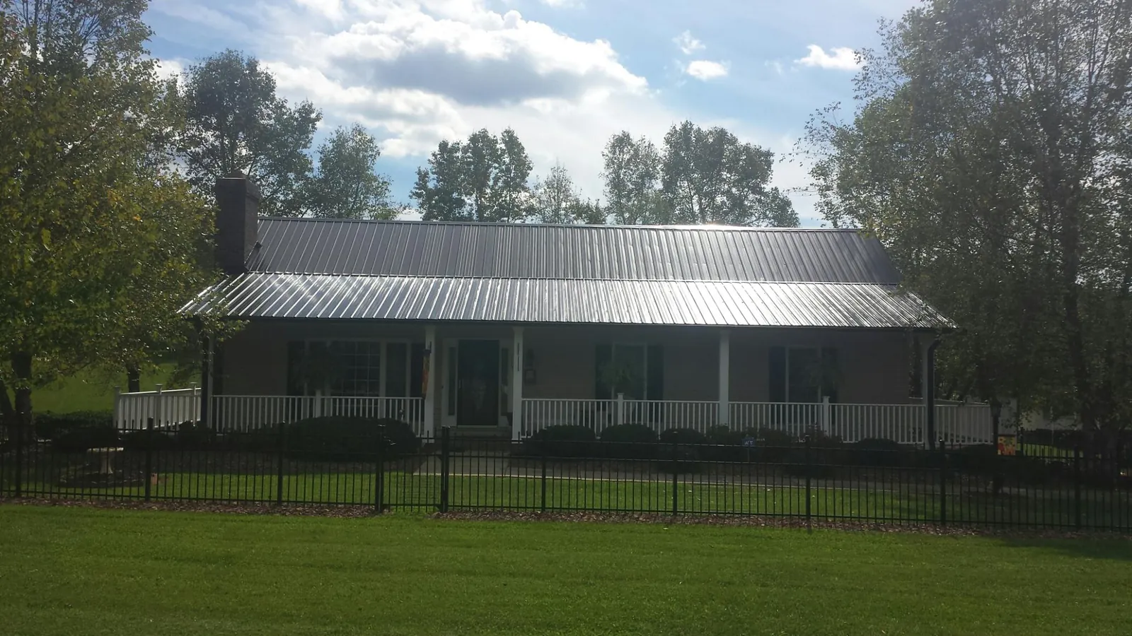 Gray metal roof on a brick ranch with a full width front porch — Gutter Guard Installation work by our crew in Hemlock